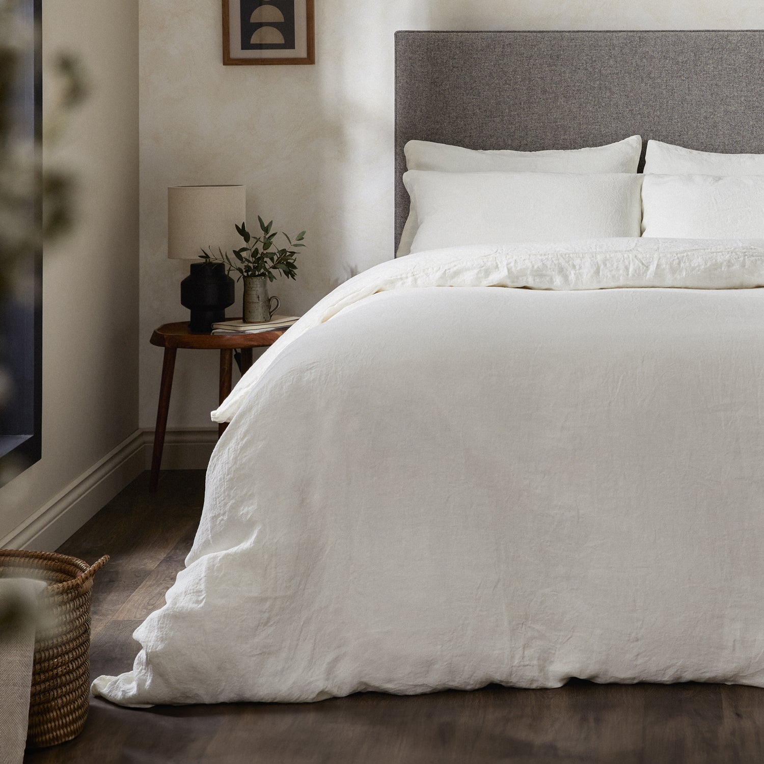 A dressed bed with Woolroom's Mariana Linen Duvet Cover in Ivory has the duvet turned down and two pillows. 