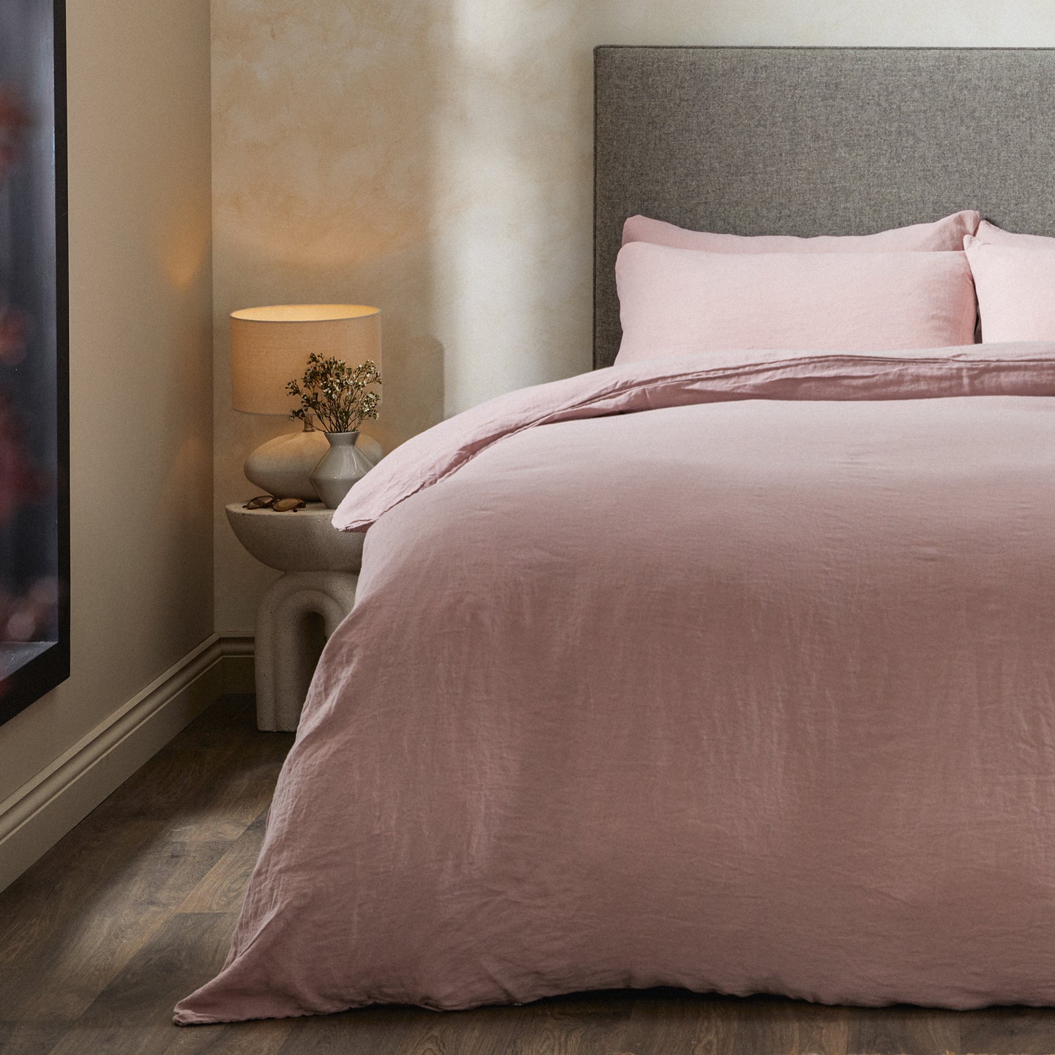 A dressed bed with Woolroom's Mariana Linen Duvet Cover in Rose has the duvet turned down and two pillows. 