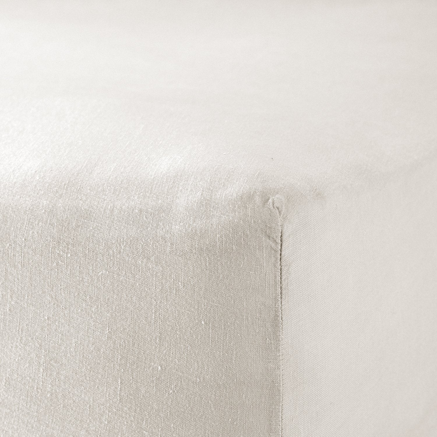 A close up of the corner of a mattress with Woolroom's Mariana Linen Blend Fitted Sheet in Ivory.
