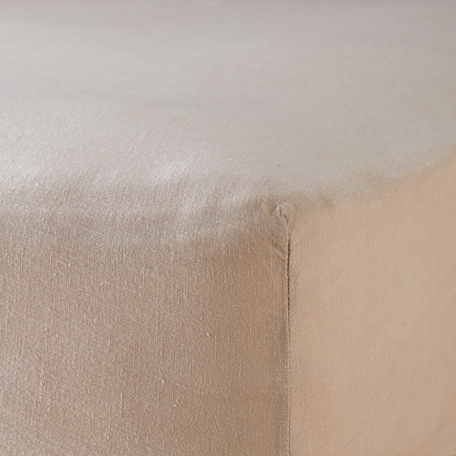 A close up of the corner of a mattress with Woolroom's Mariana Linen Blend Fitted Sheet in Sand.