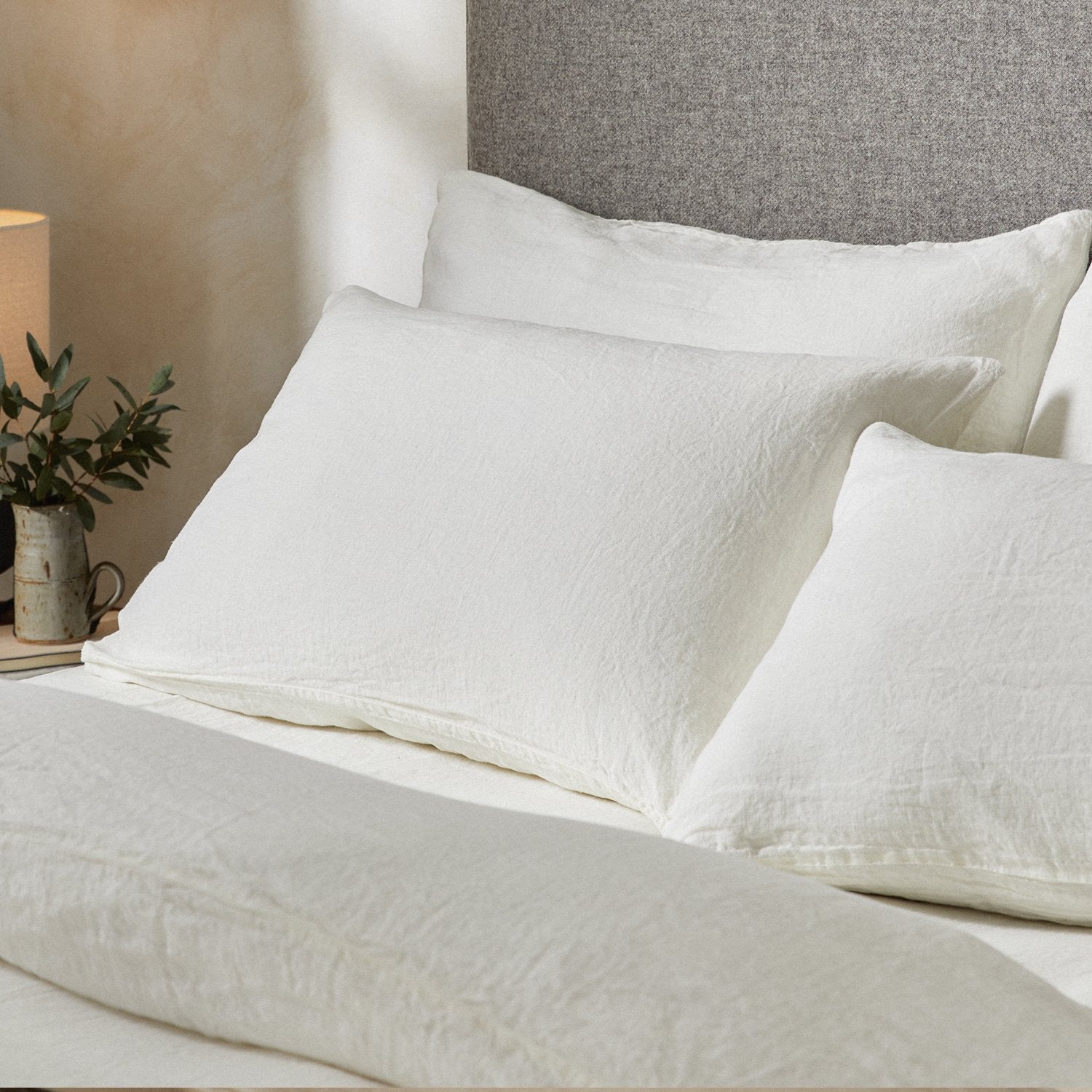 Four pillows on a dressed bed with the Mariana Linen Blend Pillow Cases in Ivory.