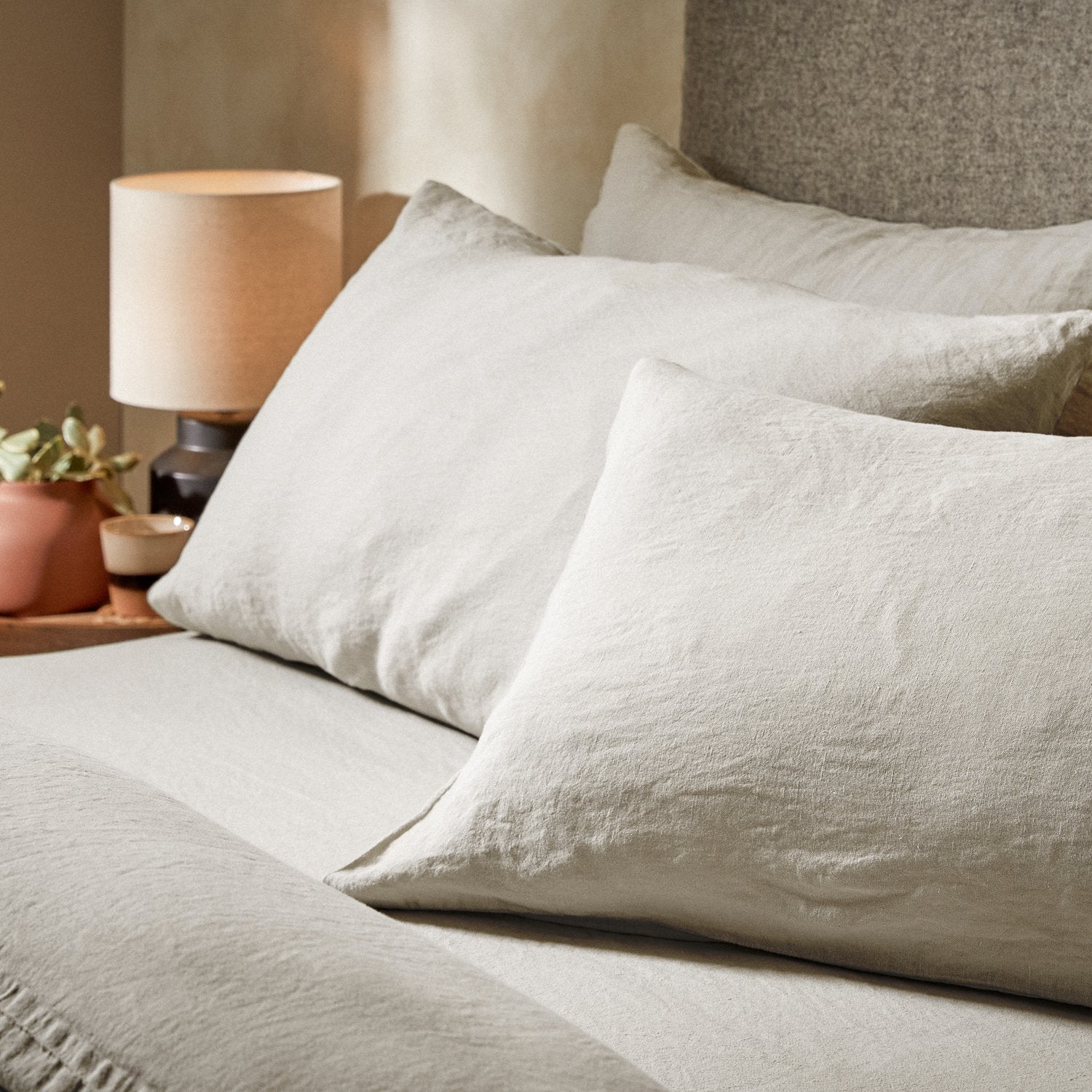 Four pillows on a dressed bed with the Mariana Linen Blend Pillow Cases in Pebble.