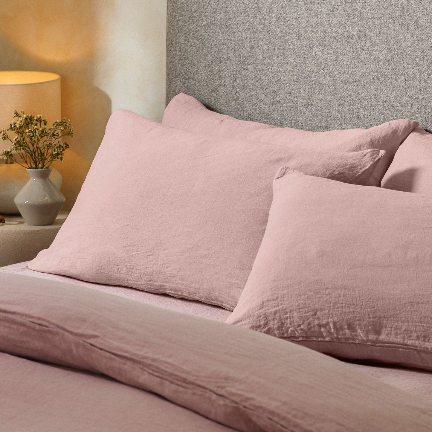 Four pillows on a dressed bed with the Mariana Linen Blend Pillow Cases in Rose.