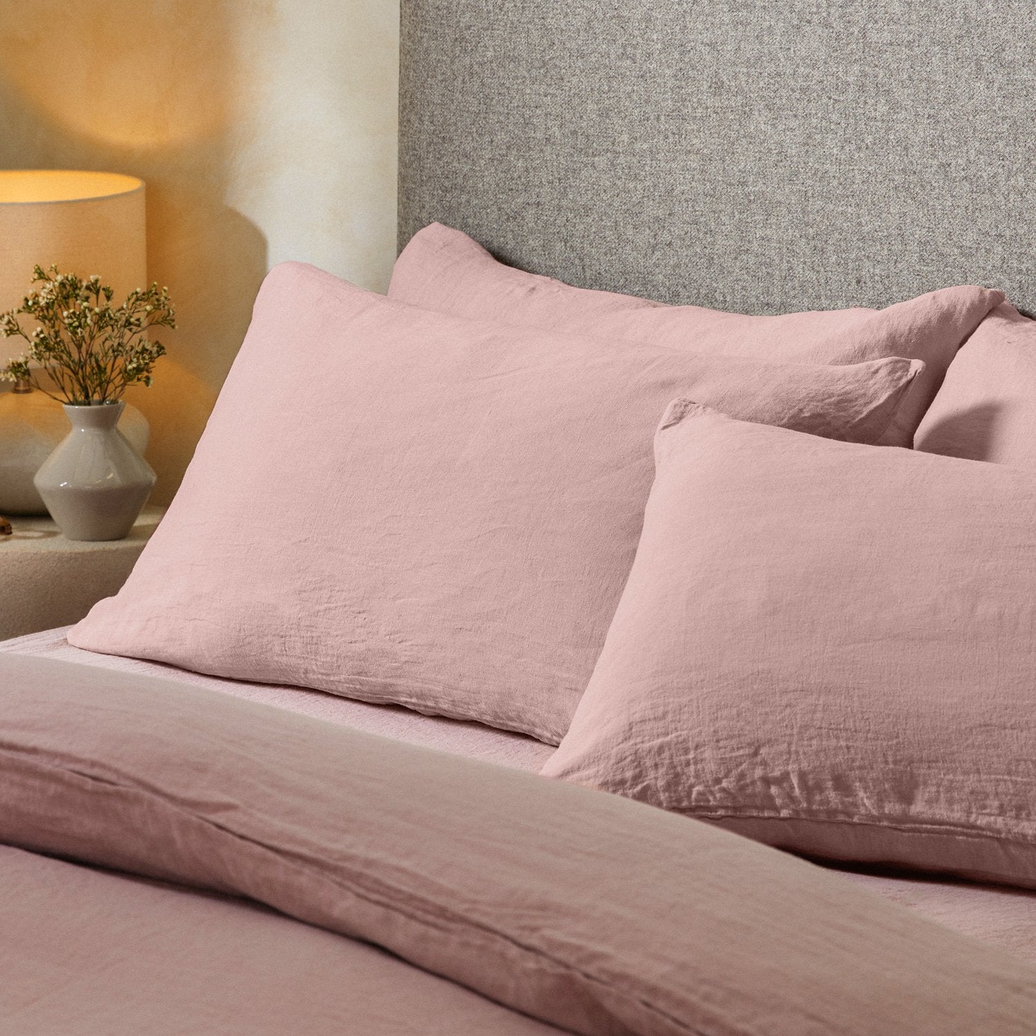 Four pillows on a dressed bed with the Mariana Linen Blend Pillow Cases in Rose.