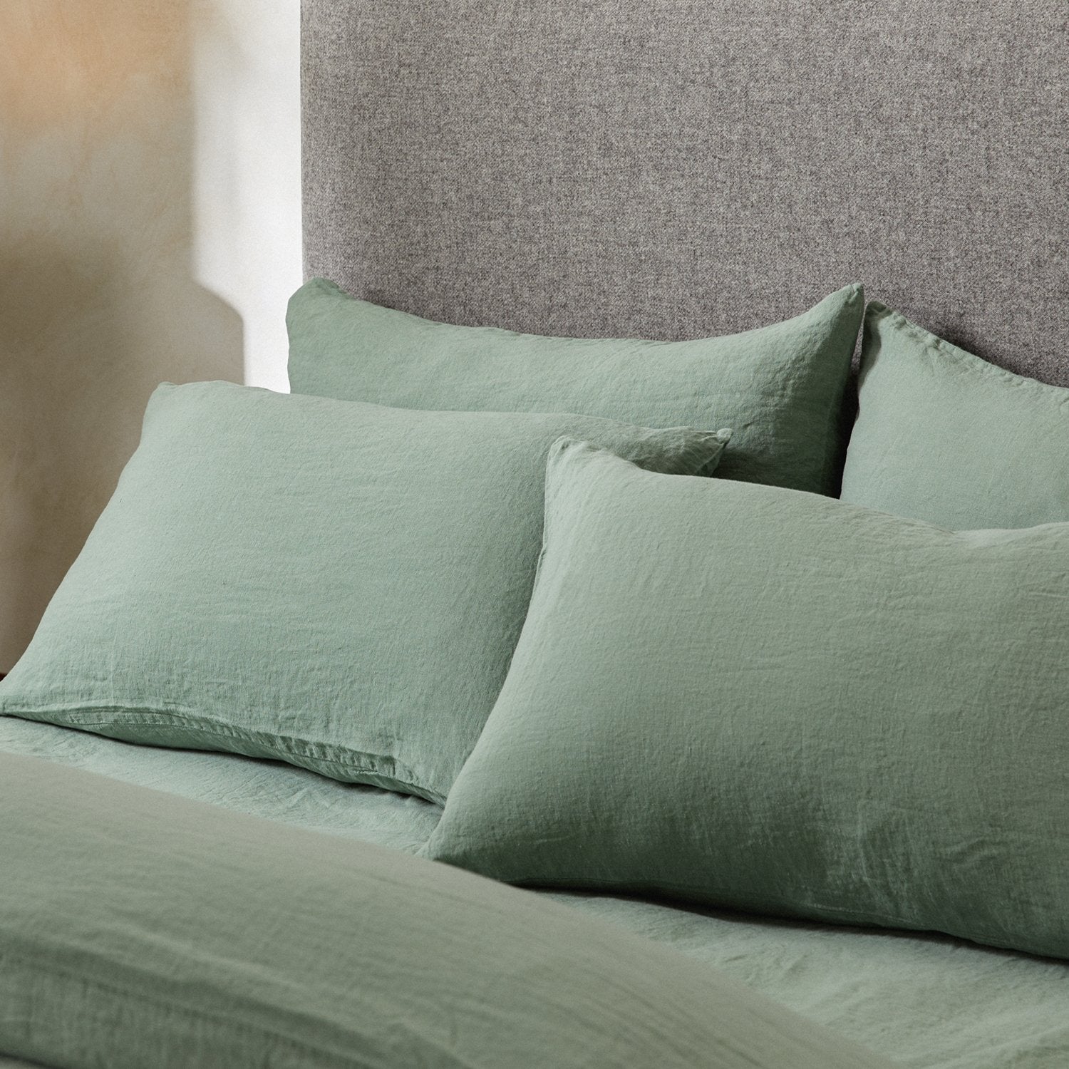 Four pillows on a dressed bed with the Mariana Linen Blend Pillow Cases in Sage.