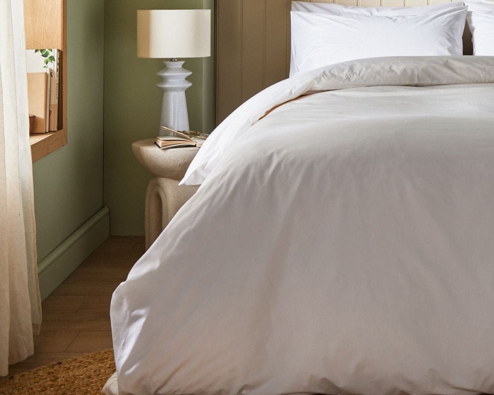 Neatly made bed with white bedding in a bedroom setting.