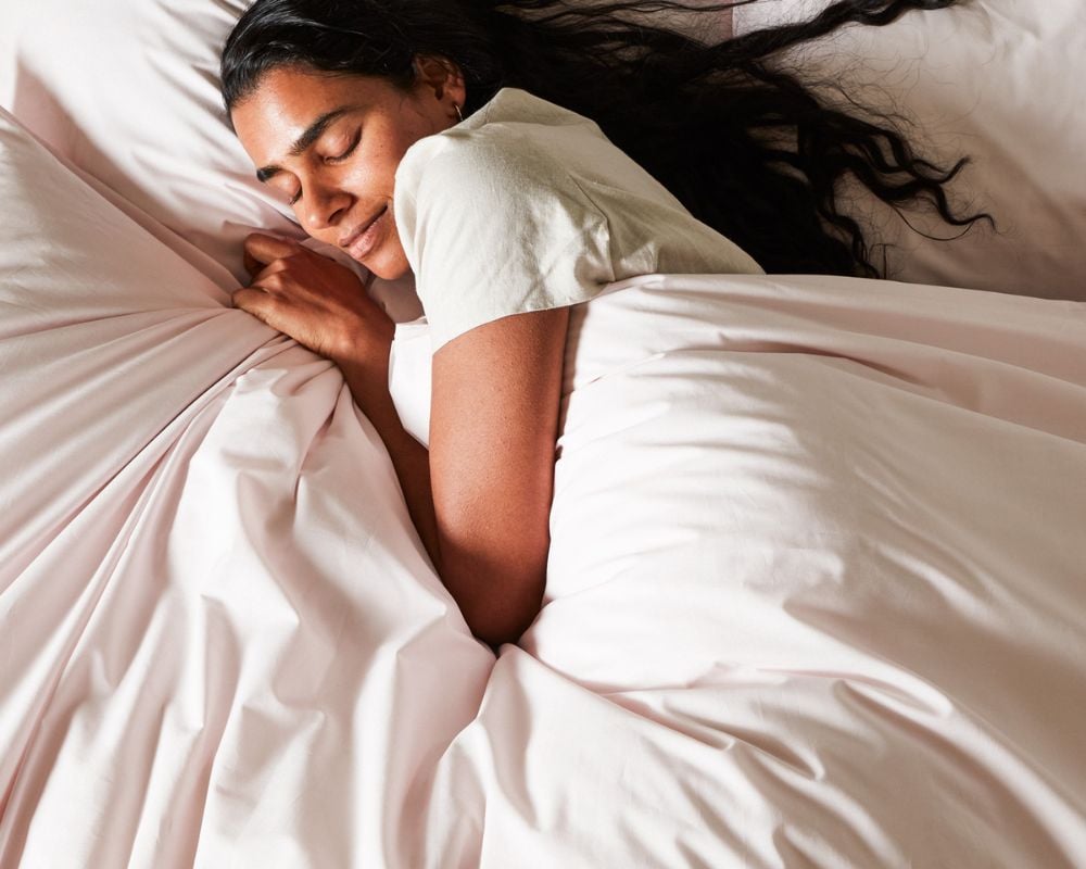 Woman sleeping peacefully under white sheets in a bedroom setting