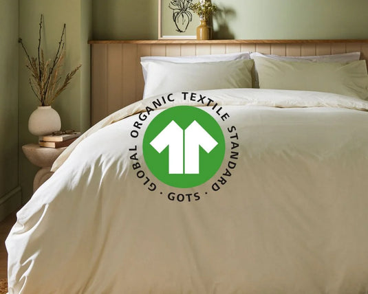 Bed with white bedding and a visible Global Organic Textile Standard logo in a bedroom setting.