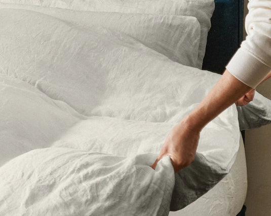 Person making a bed with white bedding